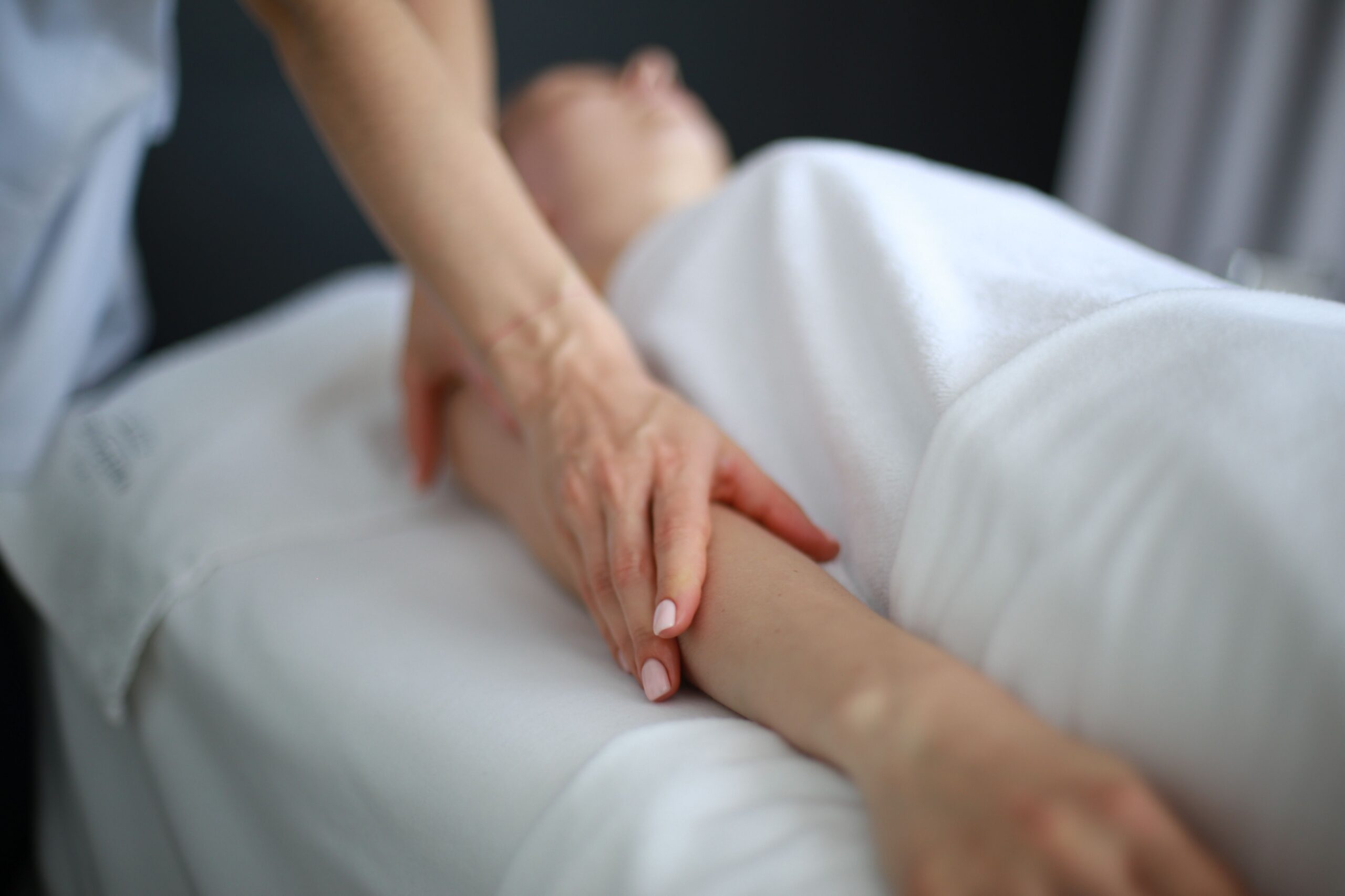 Nahaufnahme einer Massagetherapeutin, die während einer entspannenden Spa-Behandlung sanft den Arm eines Kunden massiert.