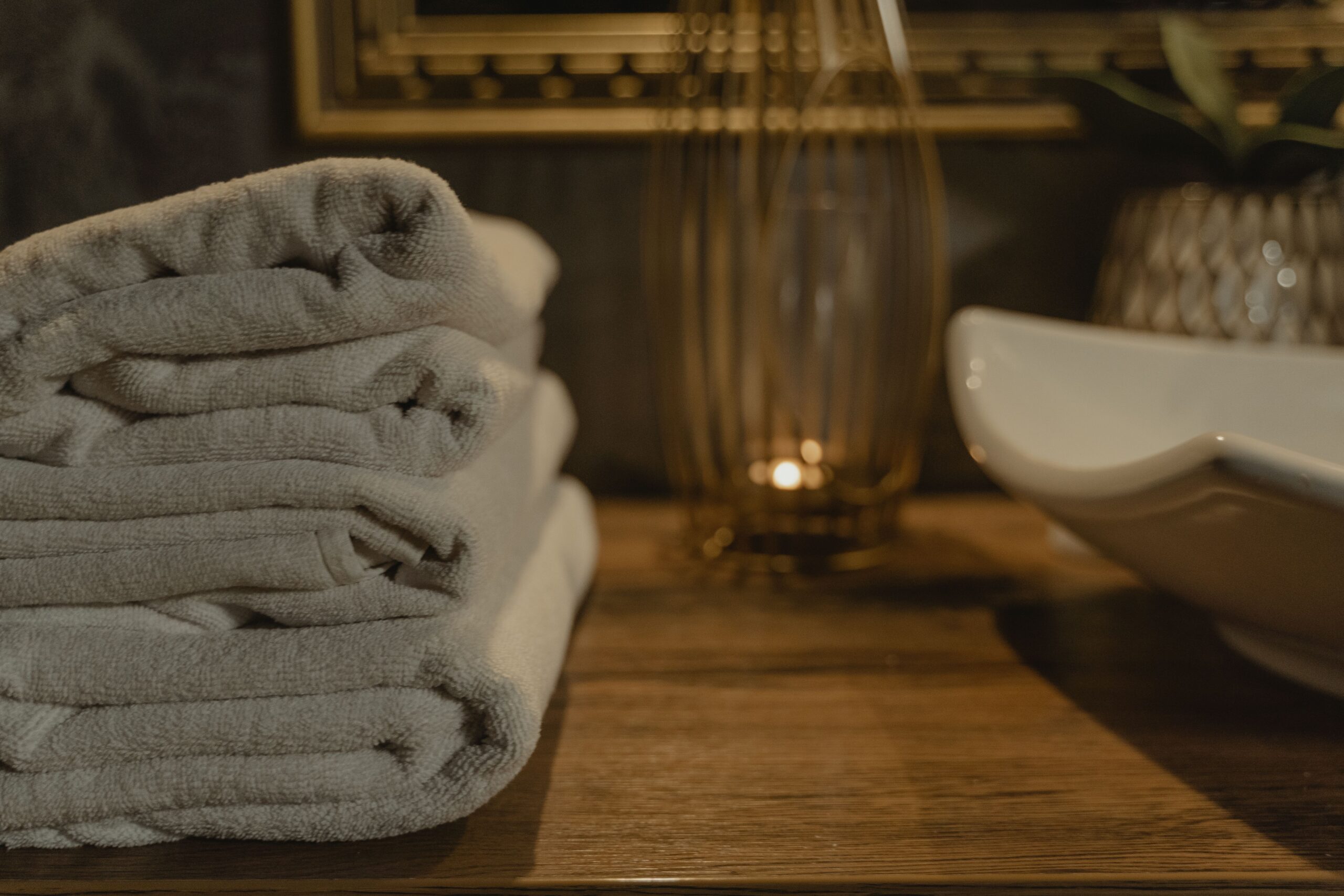 Gerollte Handtücher mit Duftkerze und Wellness-Dekoration in einem modernen Massagestudio